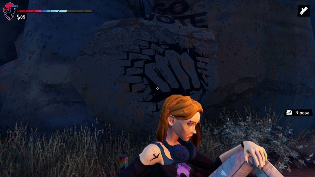 Zoe seduta davanti al fuoco con dietro il graffito di un pugno che sfonda una parete e la scritta 