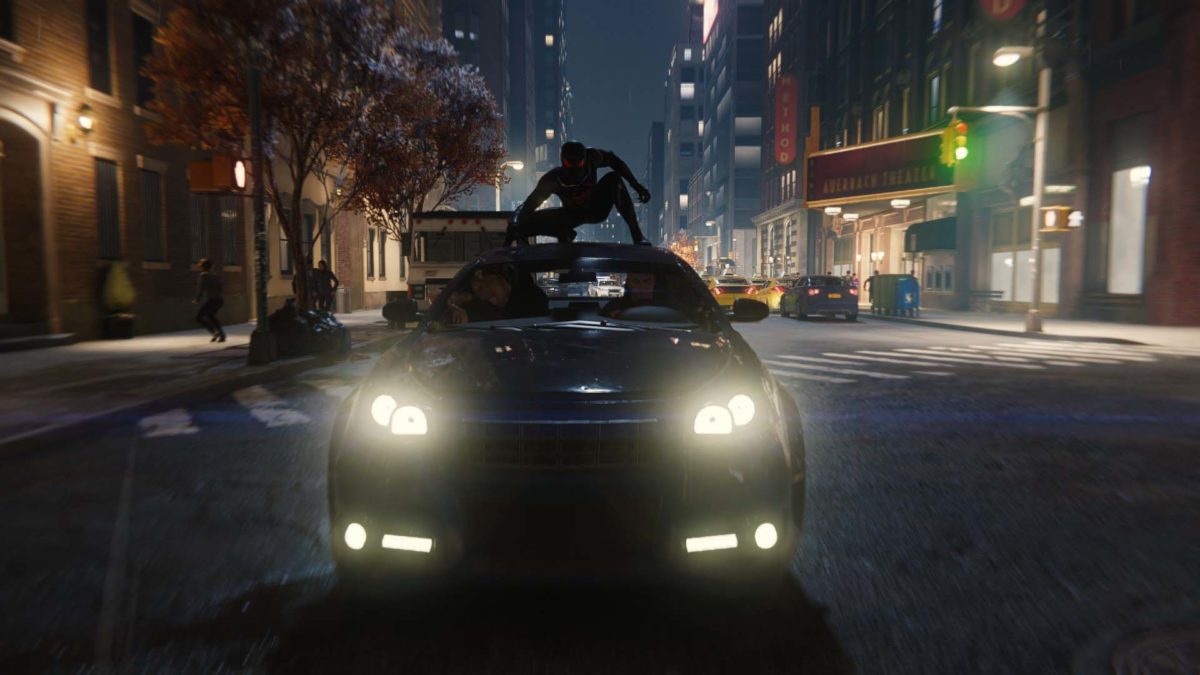Spiderman nella tuta nera sul tettuccio di un auto guidata da teppisti in fuga