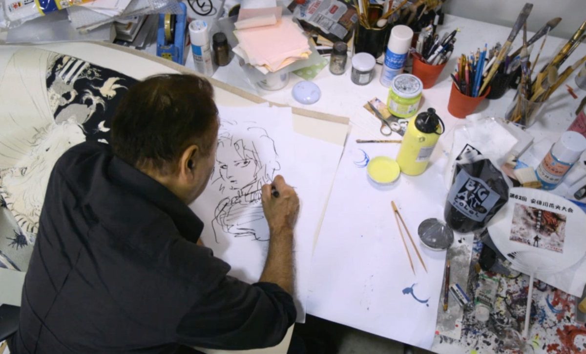 Foto che ritrae Yoshitaka Amano mentre disegna nel suo studio.
