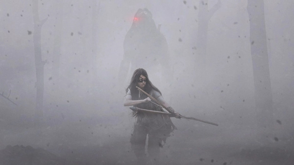 Nura è immersa nella nebbia mentre tiene teso l'arco. Dietro di lei, nell'ombra, c'è il Predator.