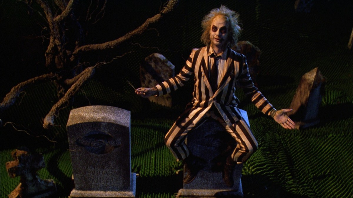 Betlejuice seduto su una lapide. Scena tratta dal flm omonimo del 1988 diretto da Tim Burton.