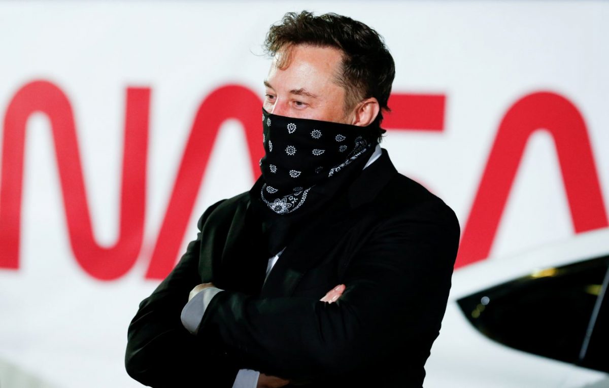 Elon Musk durante una conferenza della NASA. Una bandana nera copre la bocca del magnate.