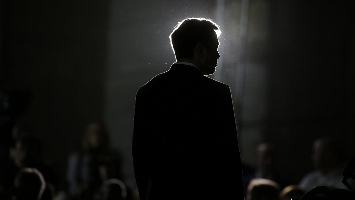 Elon Musk di spalle, avvolto nell'ombra.