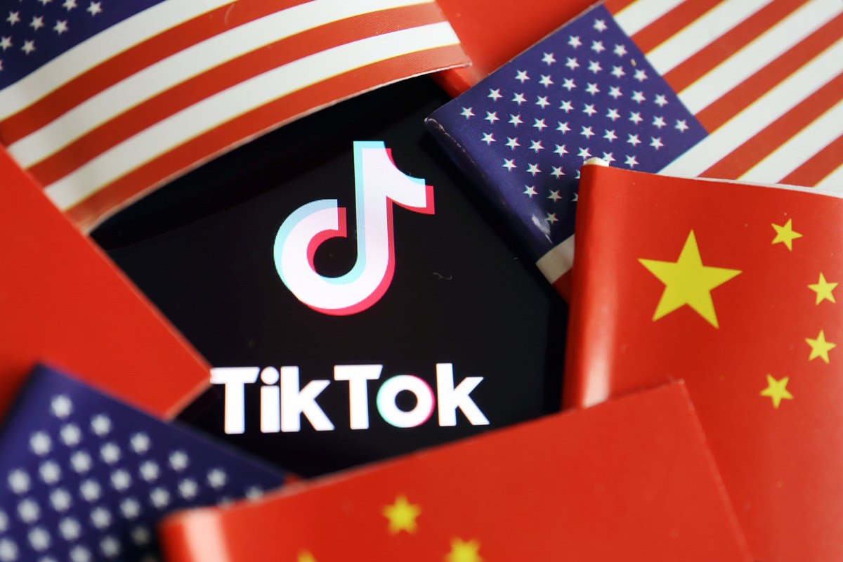 Il logo TikTok sovrastato da bandiere americane e cinesi.