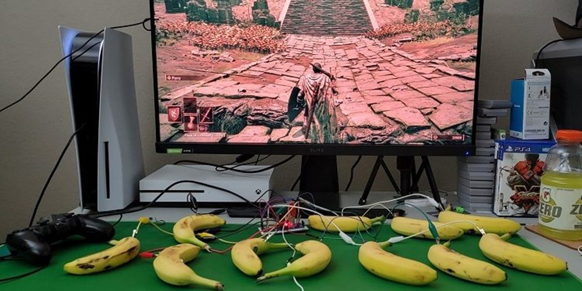 Una scrivania piena di banane collegate con dei fili alla Playstation 5 per giocare ad Elden Ring.