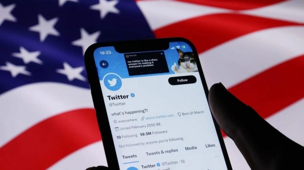 Un cellulare collegato a Twitter: dietro c'è una bandiera a stelle e strisce.