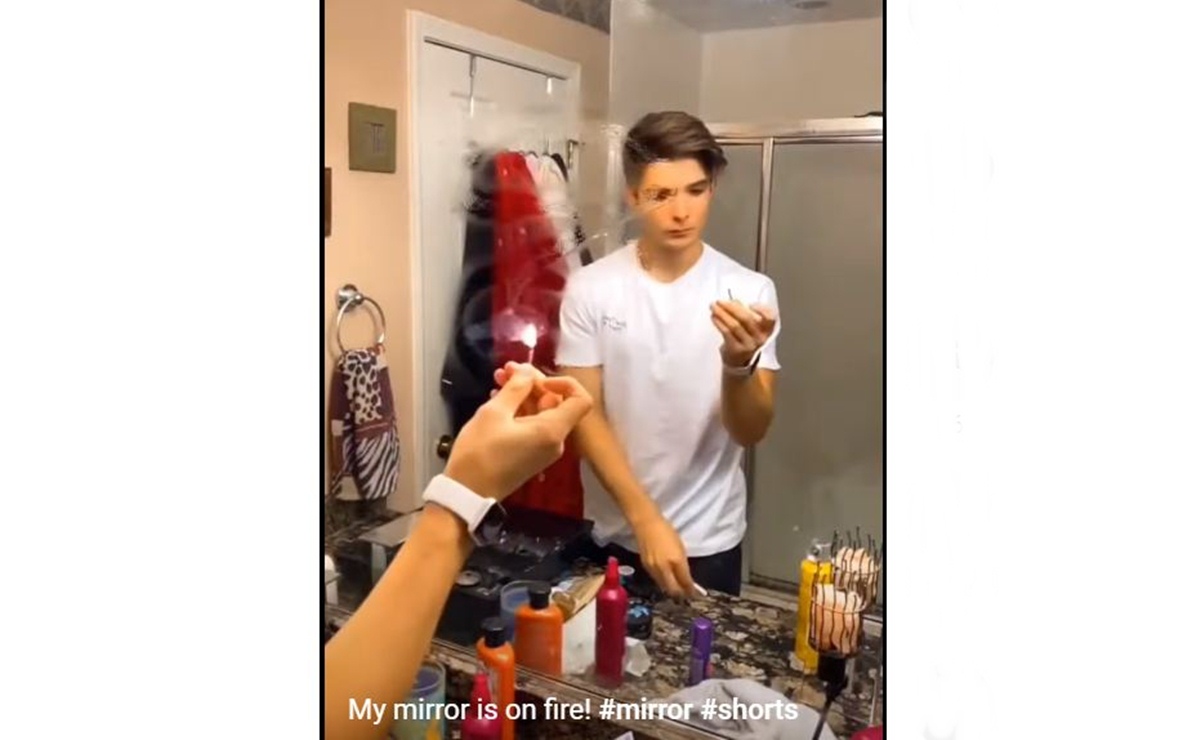 Un ragazzino sta per mettere fuoco al disegno fatto con la lacca sullo specchio.