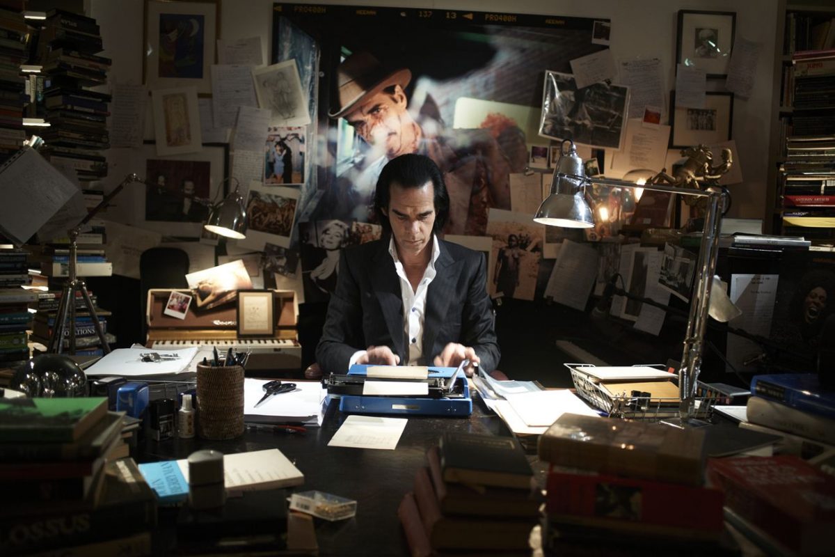 Nick Cave alla scrivania, batte sulla macchina da scrivere.