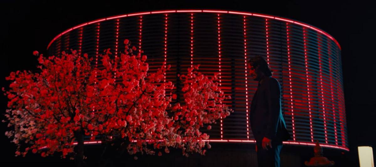 John Wick illuminato da luci rosse in una scena del quarto capitolo.