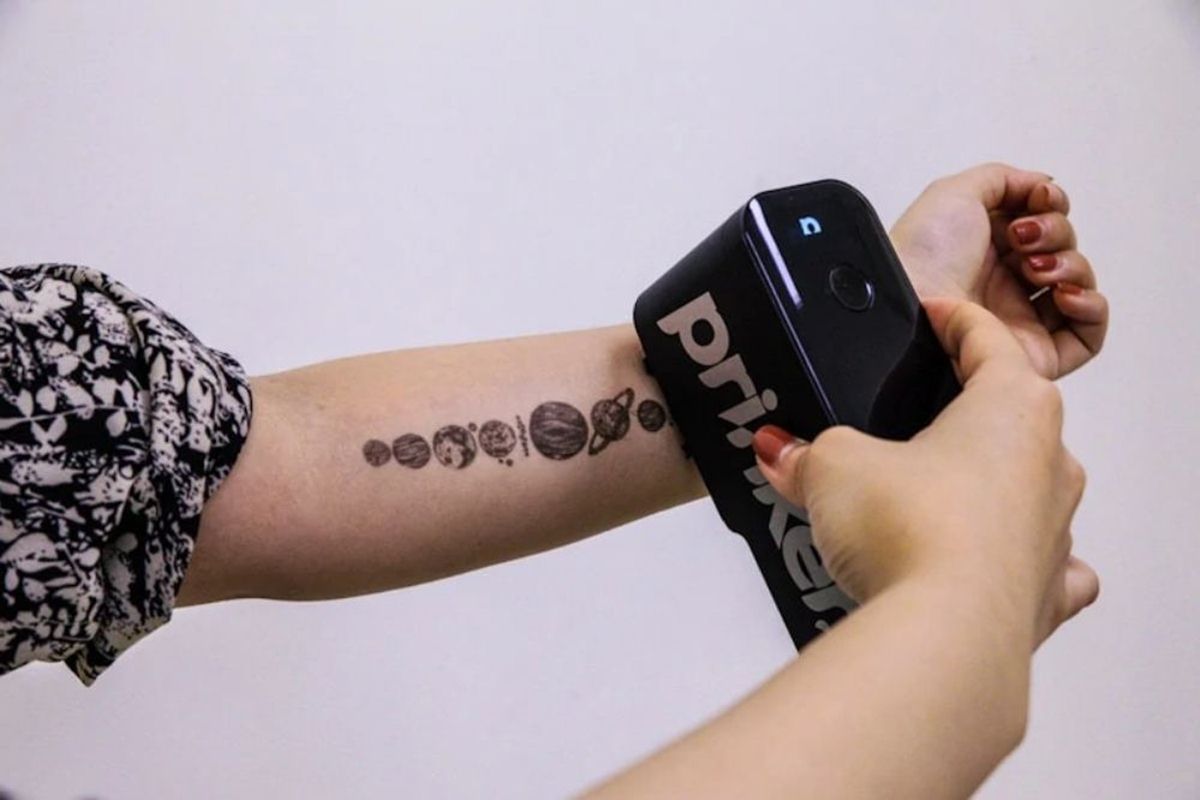 Una donna utilizza Prinker per tatuare sul proprio braccio diversi pianeti del sistema stellare.