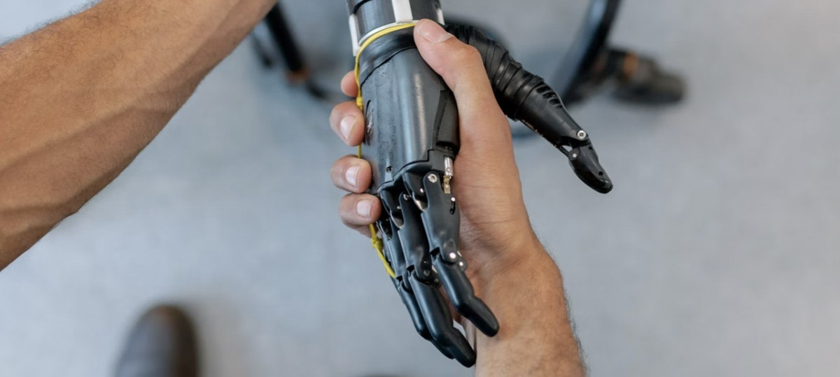 Un mano umana stringe una mano robotica.