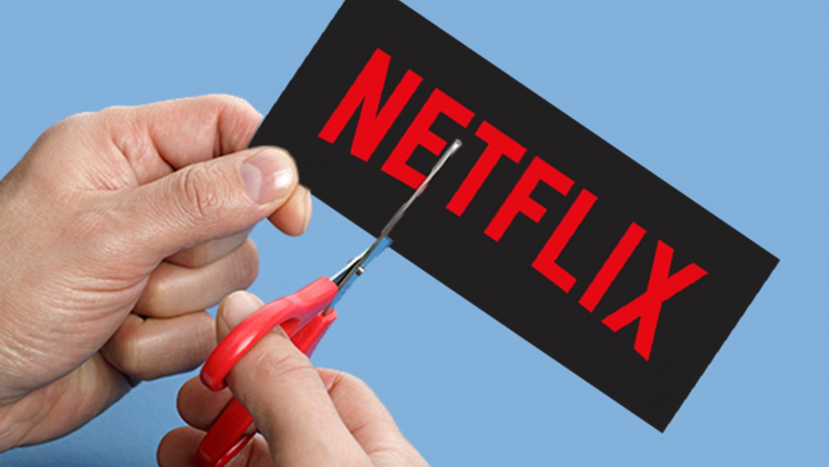 Un cartoncino con il logo Netflix viene tagliato in sue con delle forbici.