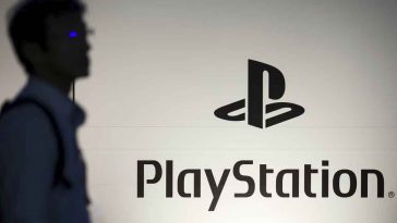 foto di un tizio che passa davanti al logo di sony playstation