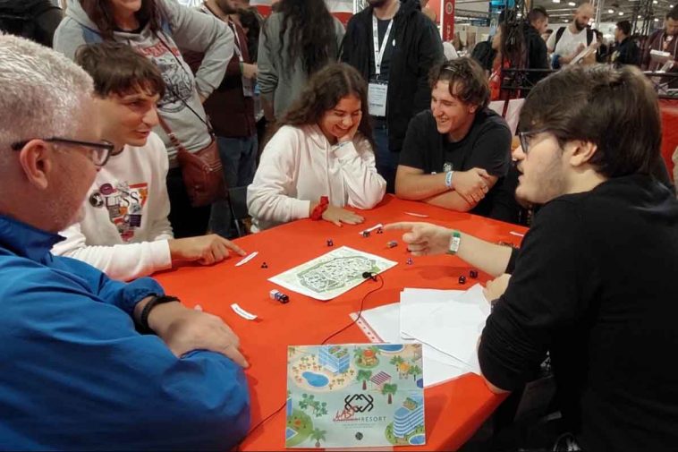 Un gruppo di persone siede attorno al tavolo con mappe e schede giocando a last resort