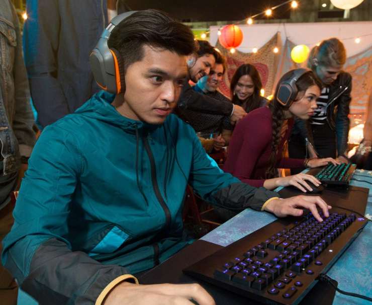 Un ragazzo al computer con una tastiera, un mouse e le cuffie