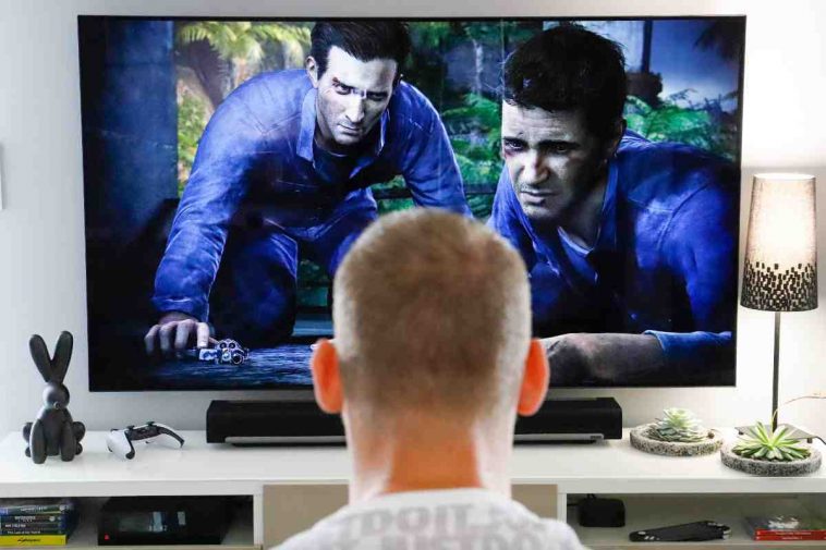 un ragazzo davanti a una tv con un videogioco e una soundbar