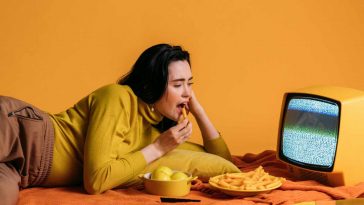 Ragazza che mangia patatine e guarda una vecchia tv senza segnale