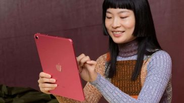 persona che sta utilizzando l'iPad seduta a un tavolo sorridendo