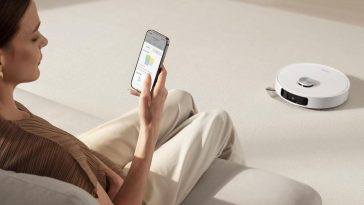 donna con cellulare controlla robot aspirapolvere