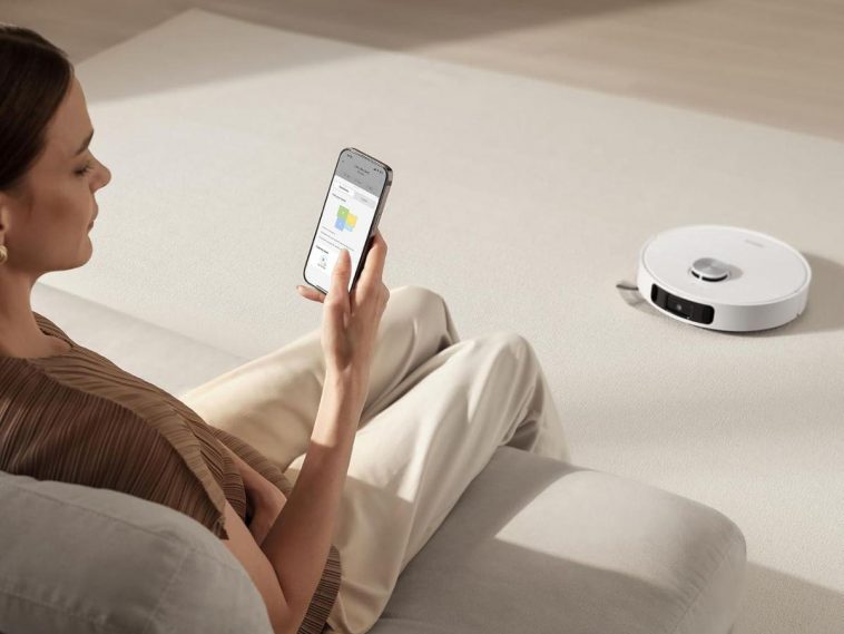 donna con cellulare controlla robot aspirapolvere