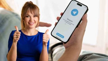 donna vestita di blu che fa i lsegno dell'ok con una donna con il cellulare e i messaggi Telegram sullo sfondo