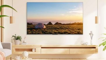 smart tv TCL appesa sulla parete in un salotto luminoso color crema