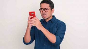 uomo arrabbiato che tiene in mano uno smartphone con cover rossa