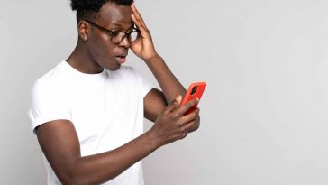 uomo sorpreso con smartphone rosso in mano