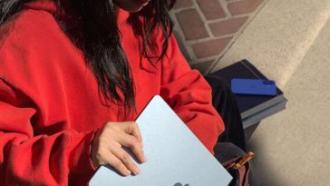 ragazza con felpa rossa mette MacBook nello zaino