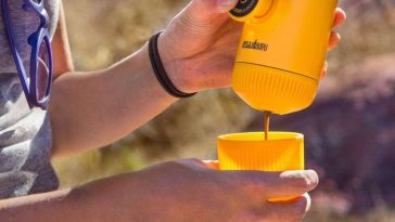 ragazzo in montagna versa caffè dalla macchinetta in tazzina di plastica