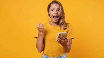 donna con il telefono contenta vestita di arancione