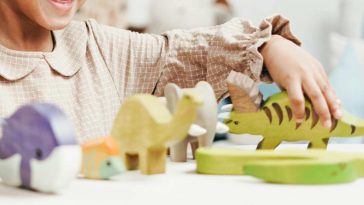 Una bambina sorridente alle prese con vari animaletti- giocattolo