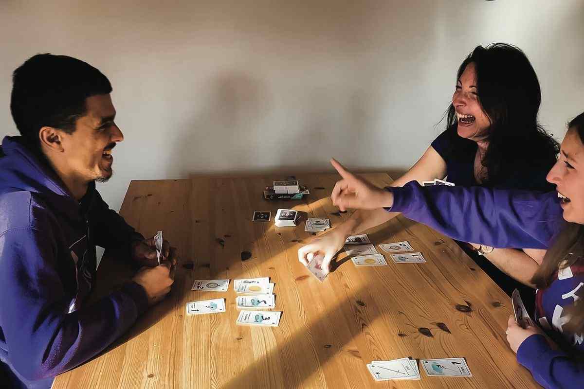 Tre ragazzi giocano a carte attorno a un tavolo