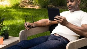 uomo sdraiato in giardino con ereader