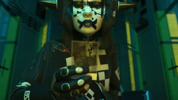 personaggio femminile di Marathon con spuntoni in testa, faccia bianca e tuta robotica che tiene in mano una fotografia