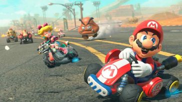 screenshot di Mario Kart World con Mario che sterza sulla strada, dietro di lui Peach che sterza sulla moto e ancora dietro un Goomba gigante che insegue