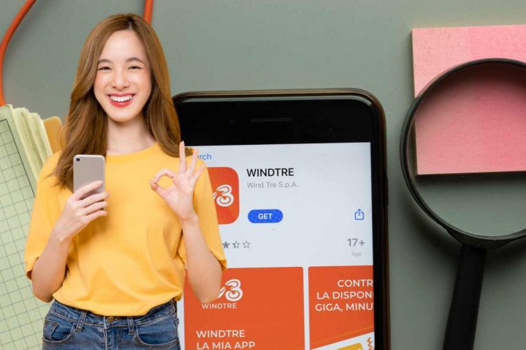 smartphone con app windtre e ragazza con il cellulare in mano che sorride