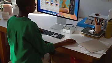 persona seduta alla scrivania che usa il Mac Mini con schermo apple