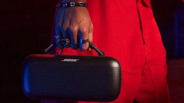 Ragazzo vestito di rosso trasporta cassa Bose dal manico