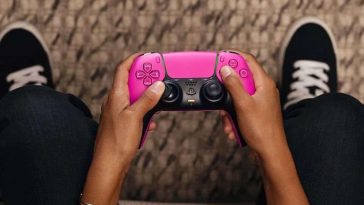 persona che tiene in mano un DualSense rosa