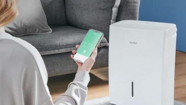 ragazza tiene in mano cellulare con deumidifcatore di fronte