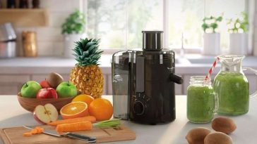 estrattore di frutta in cucina su banco con accanto frutta fresca su tagliere