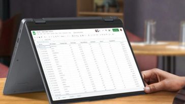Lenovo IdeaPad Flex 5 su tavolino di legno con accanto mano di utilizzatore