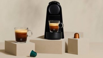 Nespresso Essenza Mini macchina del caffè su sfondo beige su blocchi con caffe e capsule