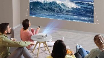 famiglia che guarda uno schermo proiettato con sopra dei delfini e il mare