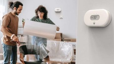 coppia in salotto che mballa mobili, al muro appeso rlevatore di radon