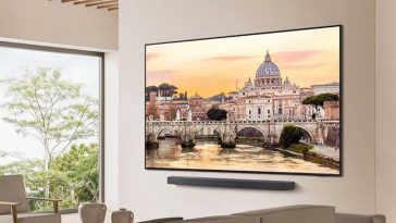 smart tv samsung in salotto appeso al muro, sotto soundbar, davanti divano