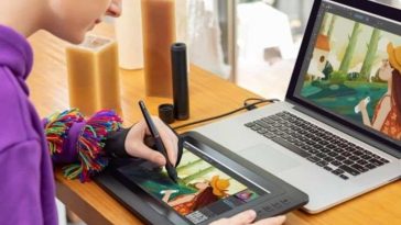 ragazza davanti a computer disegna su tavoletta grafica