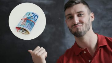 Un ragazzo soddisfatto che indica degli euro arrotolati