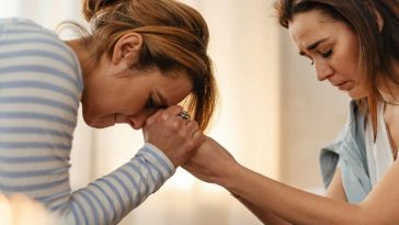 Due donne angosciate si stringono le mani